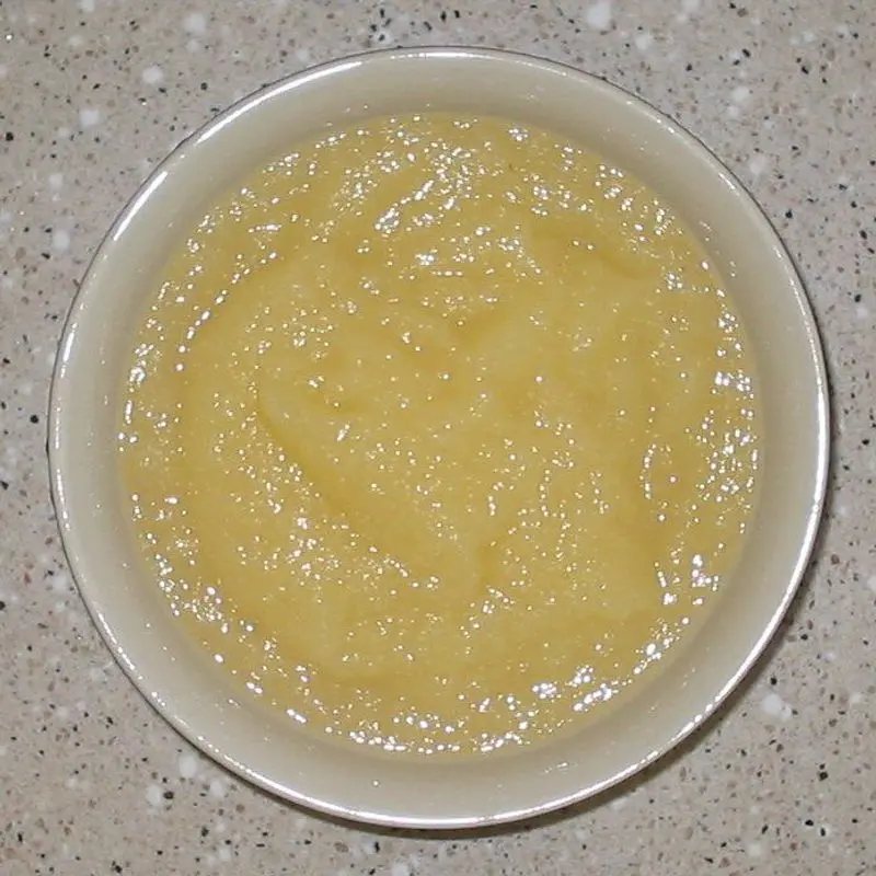 Plato hondo lleno de compota de manzana suave de color pálido