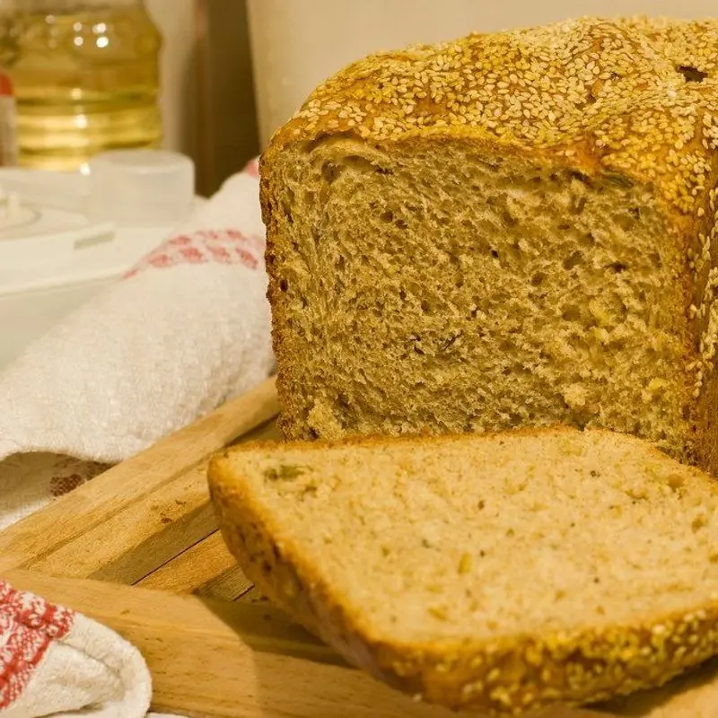 Pan de cereales con semillas, con una rebanada cortada, sobre una tabla de madera