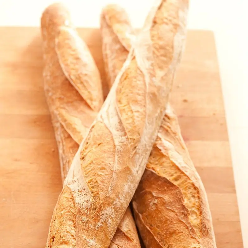 Tres barras de pan baguette crujientes y doradas sobre fondo claro