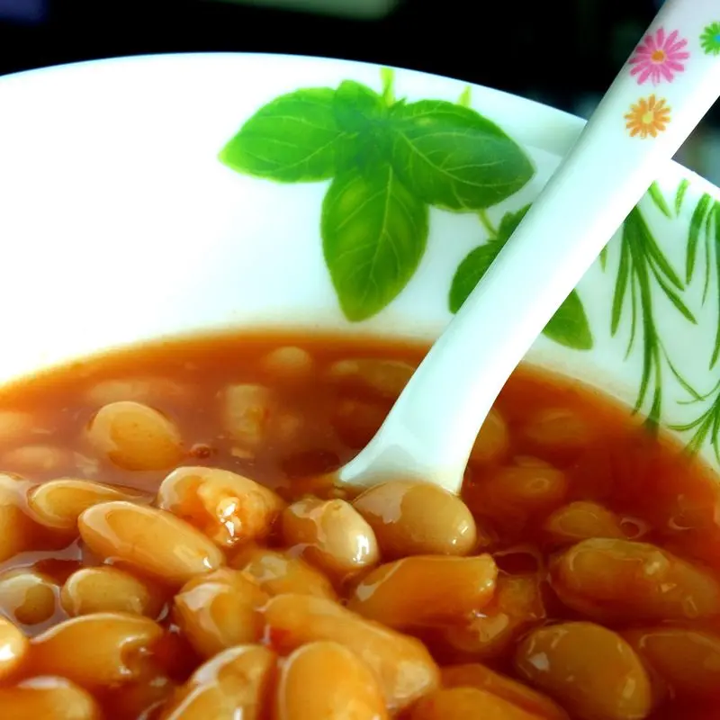 Cuenco de alubias blancas en salsa de tomate con una cuchara blanca