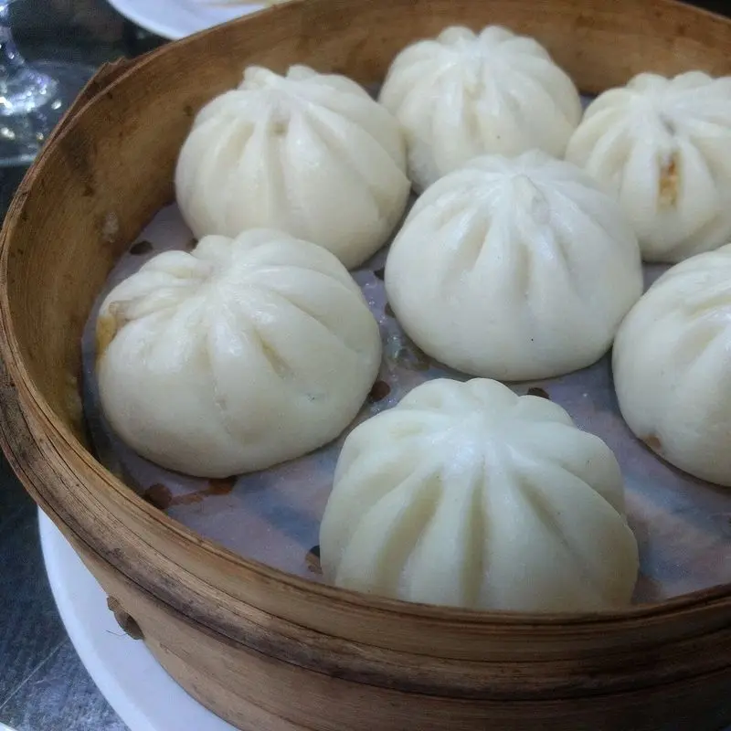 Bollitos blancos al vapor en una cesta de bambú