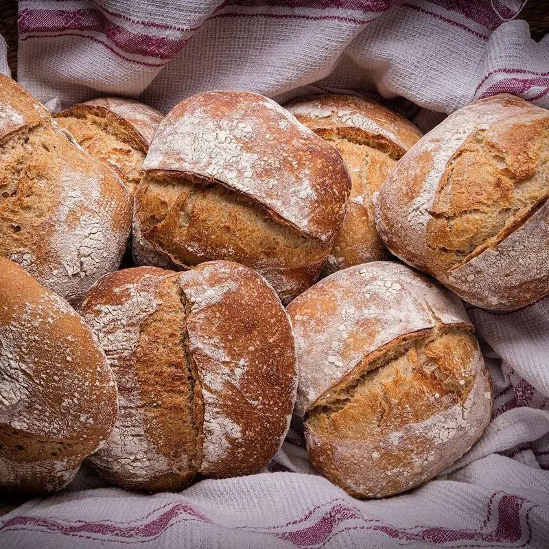 Panecillos rústicos enharinados en una cesta con paño a rayas