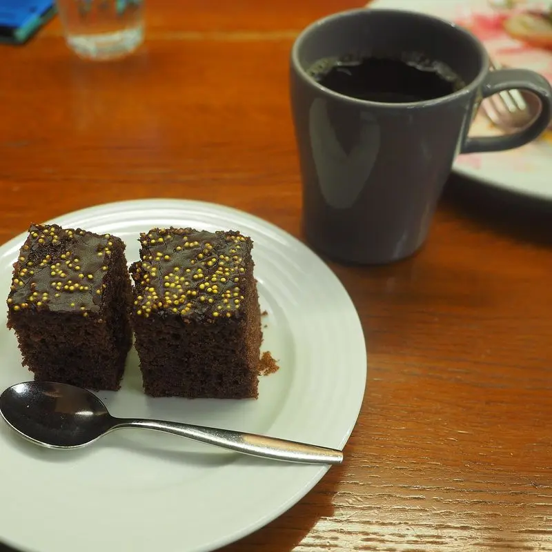 Dos brownies de chocolate en un plato blanco junto a una taza de café
