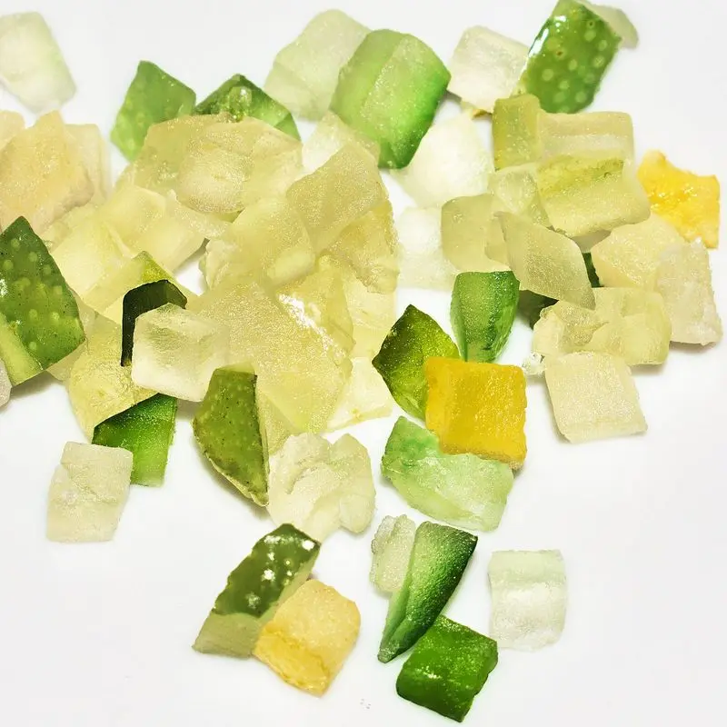 Dados de fruta confitada de colores verde, amarillo y blanco sobre fondo blanco