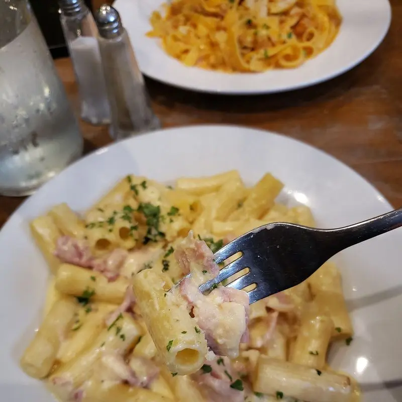 Rigatoni con salsa carbonara cremosa y trocitos de beicon en un plato