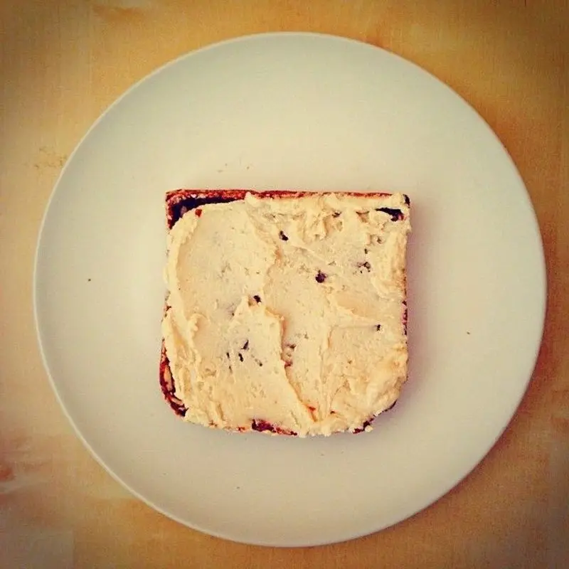 Rebanada de pan tostado untada con crema de anacardos sobre un plato blanco