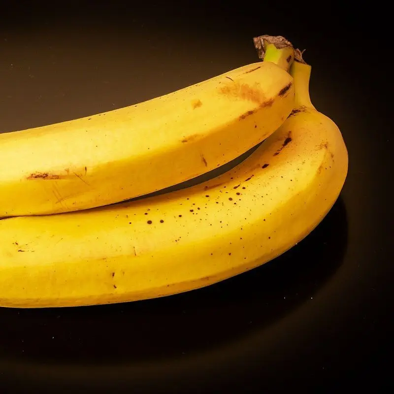 Dos plátanos amarillos maduros sobre fondo negro