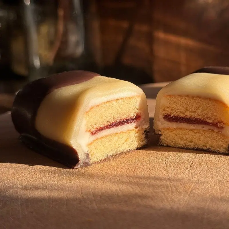 Pastelito de bizcocho cortado por la mitad con cobertura de chocolate y relleno de mermelada