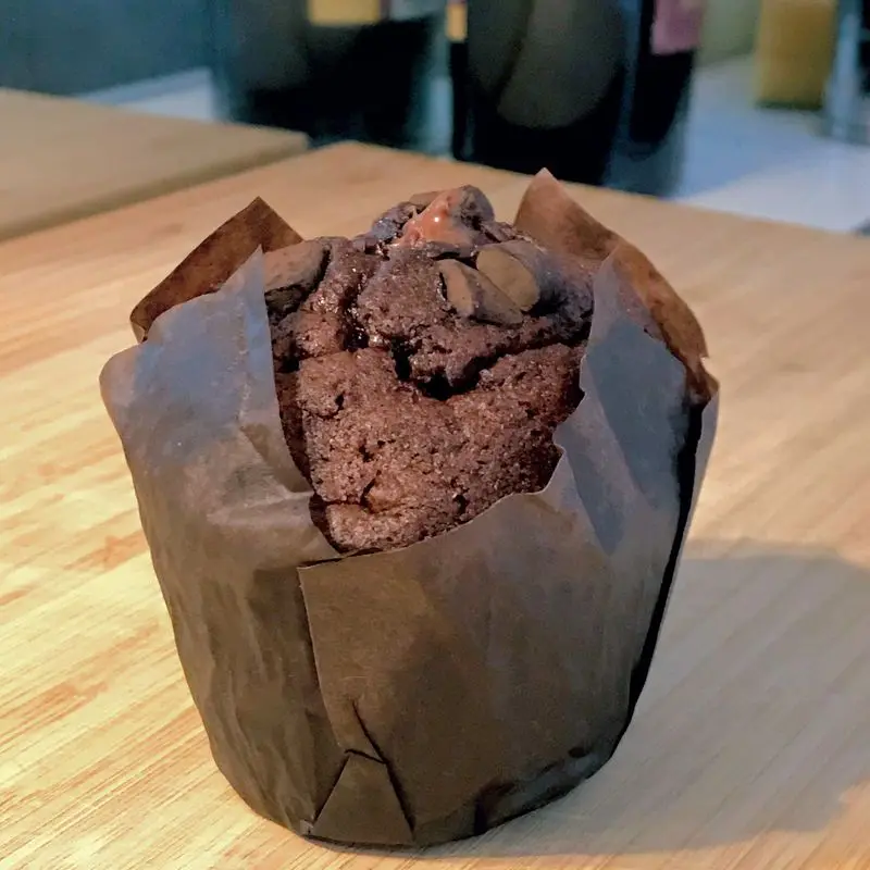 Muffin de chocolate en su cápsula de papel marrón sobre una mesa de madera