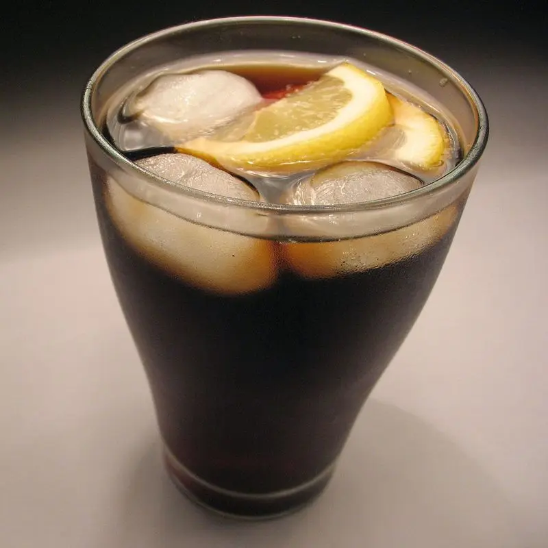 Vaso de refresco de cola con hielo y una rodaja de limón