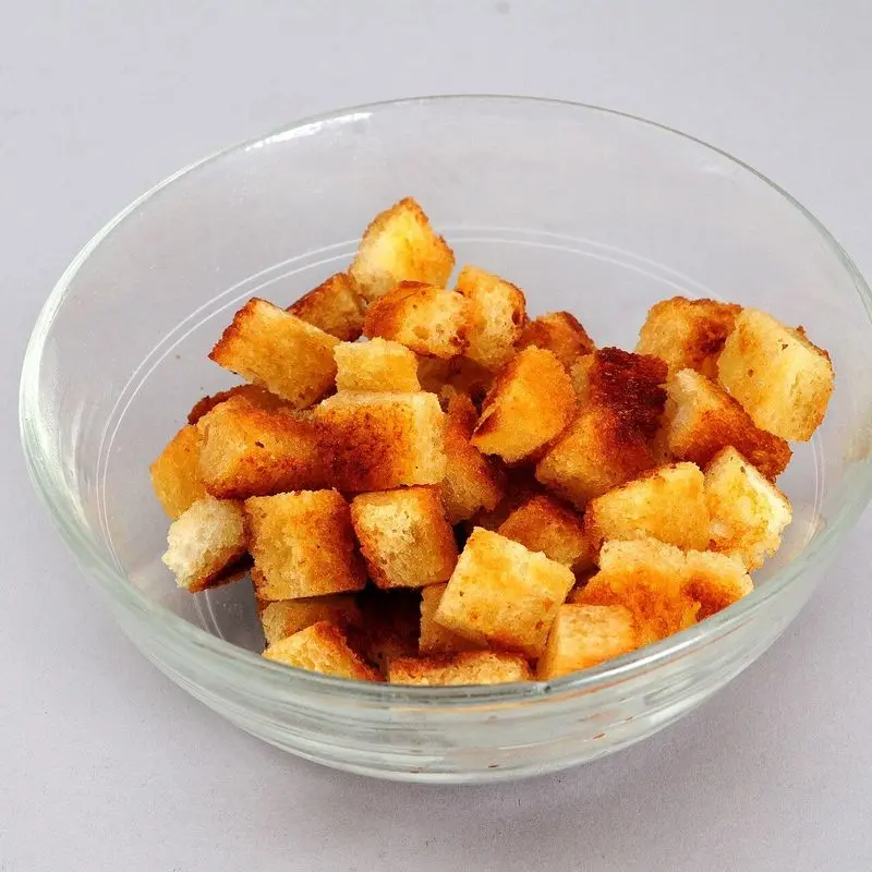 Cuenco de cristal con cuadraditos de pan tostado dorado