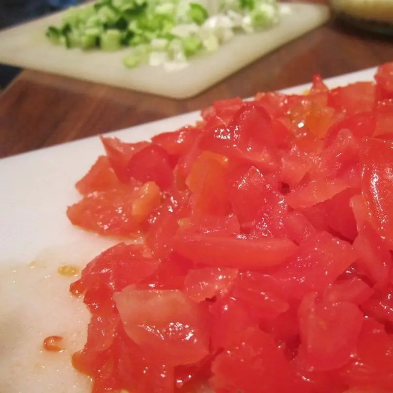 Tomate rojo picado muy fino sobre una tabla blanca