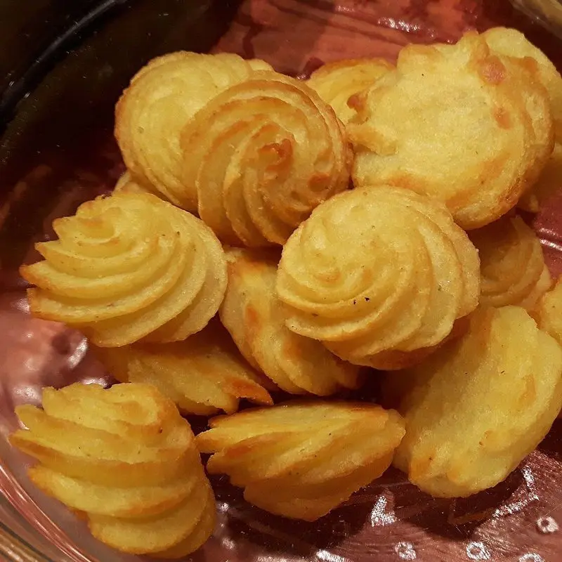 Patatas duquesa en forma de rosetón doradas en una fuente