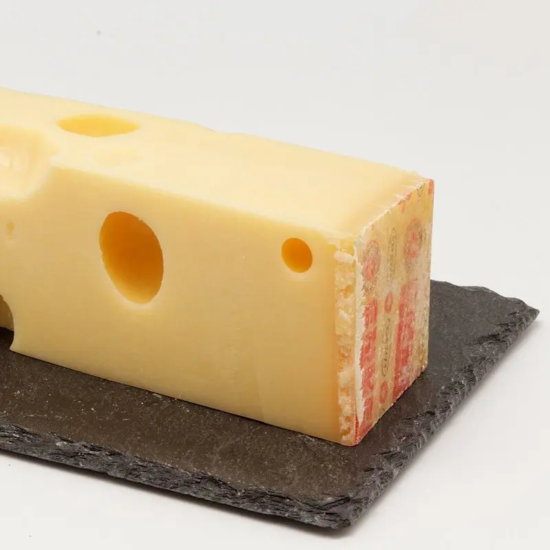 Bloque de queso emmental con agujeros sobre una pizarra