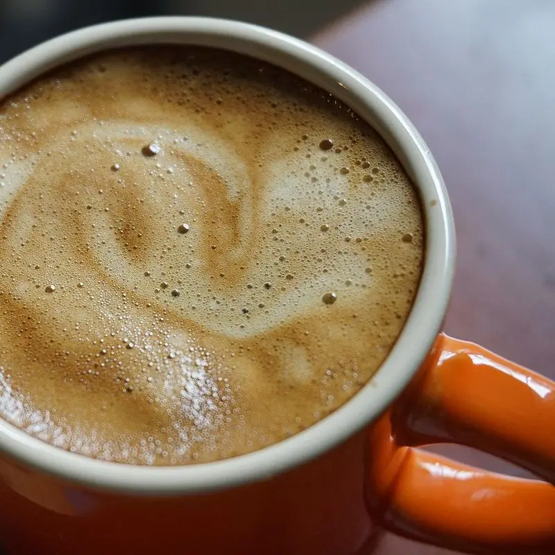 Taza naranja de café espresso con crema de espuma marrón vista desde arriba