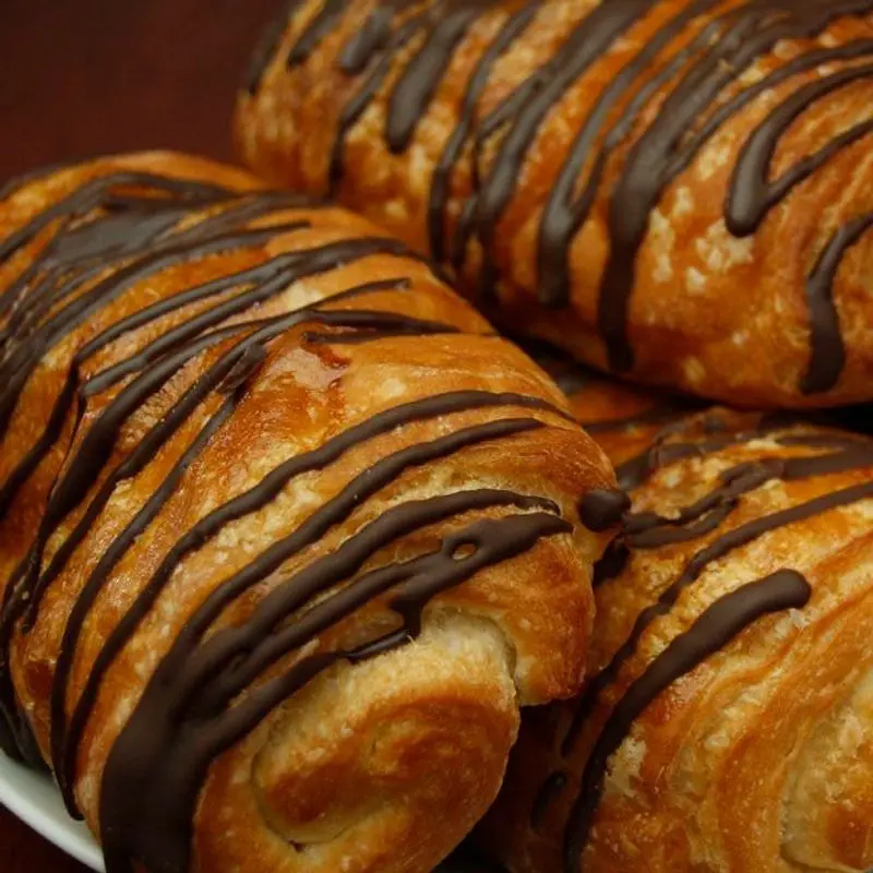 Bollos de masa dorada rellenos de chocolate con tiras de chocolate por encima