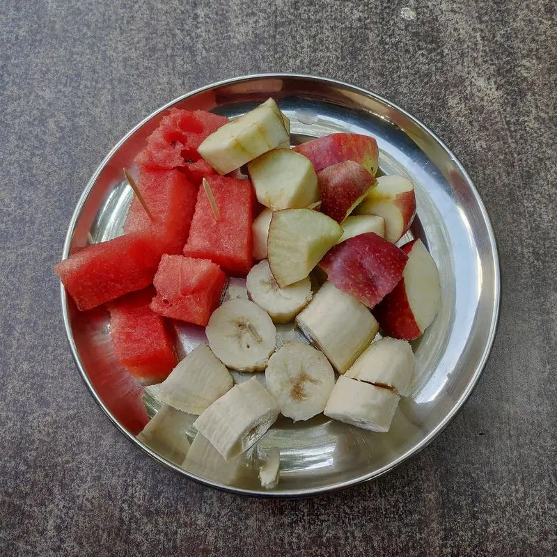 Macedonia de sandía, plátano y otras frutas troceadas en una bandeja metálica
