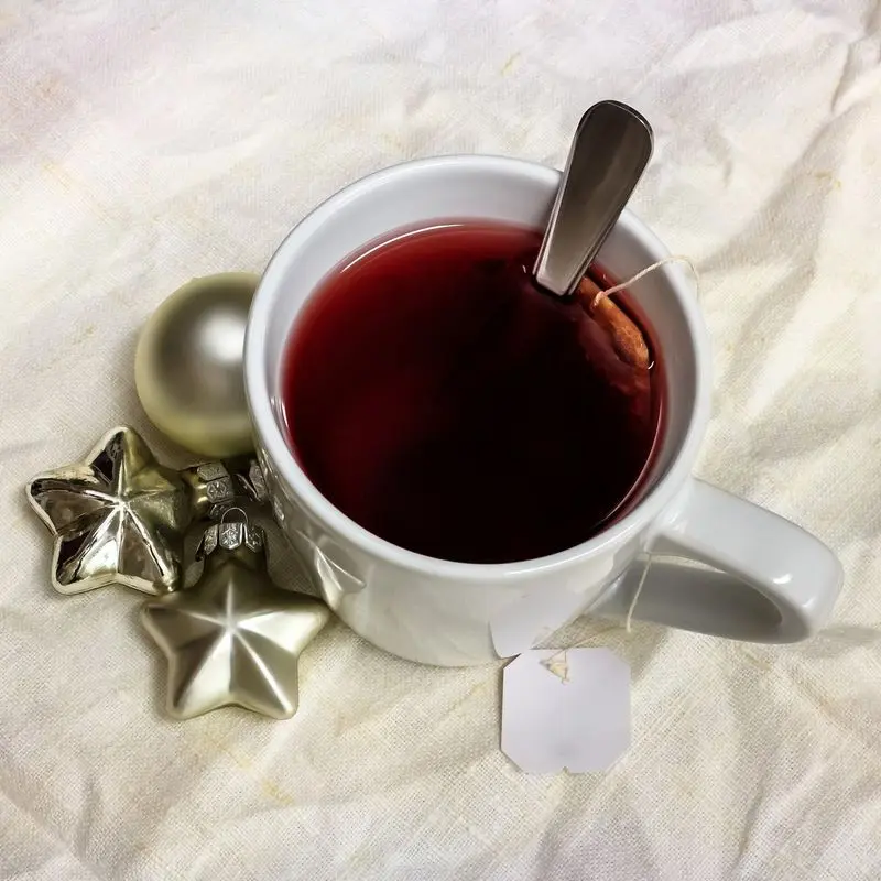 Taza blanca con infusión de frutos rojos de color rojo intenso y una cucharilla