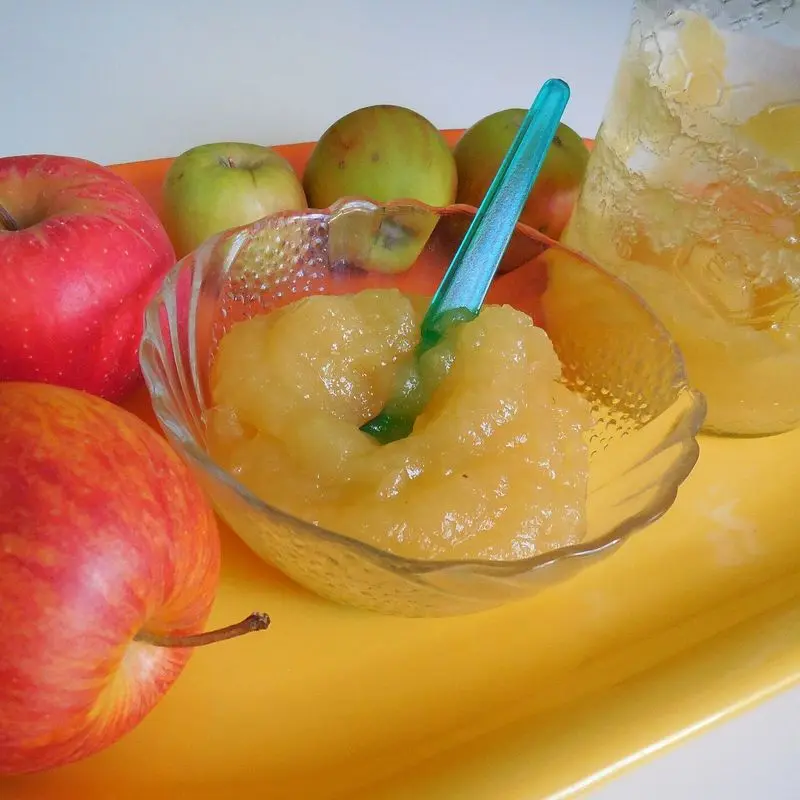 Cuenco de puré de manzana casero con manzanas rojas alrededor