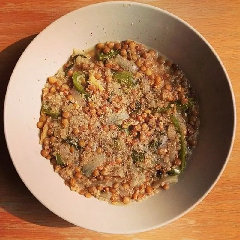 Cuenco con una mezcla cocida de quinoa y lentejas con verduras picadas