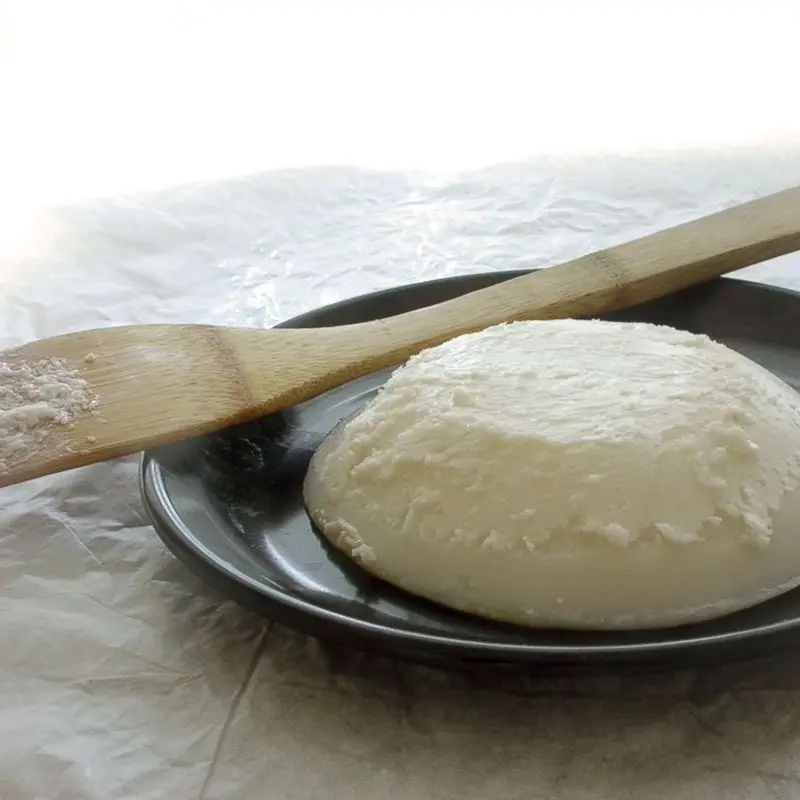 Manteca de cerdo blanca sobre un plato oscuro con una espátula de madera