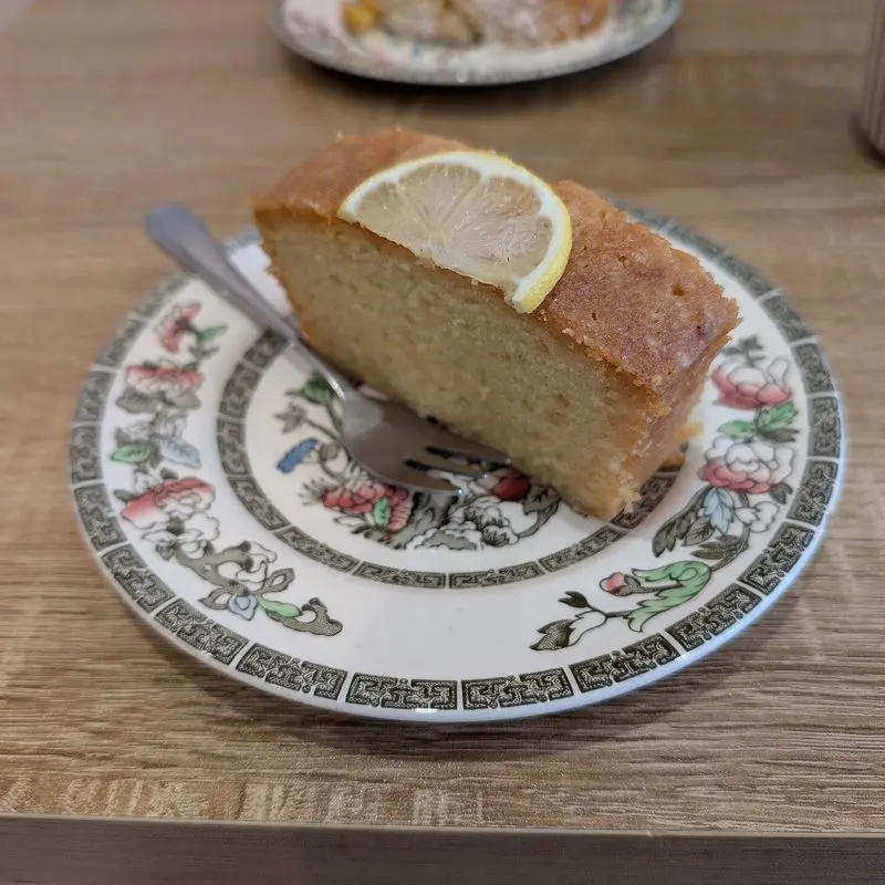 Porción de bizcocho de limón con una rodaja de limón sobre un plato decorado