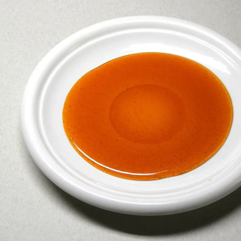Caramelo líquido ámbar extendido sobre un plato blanco