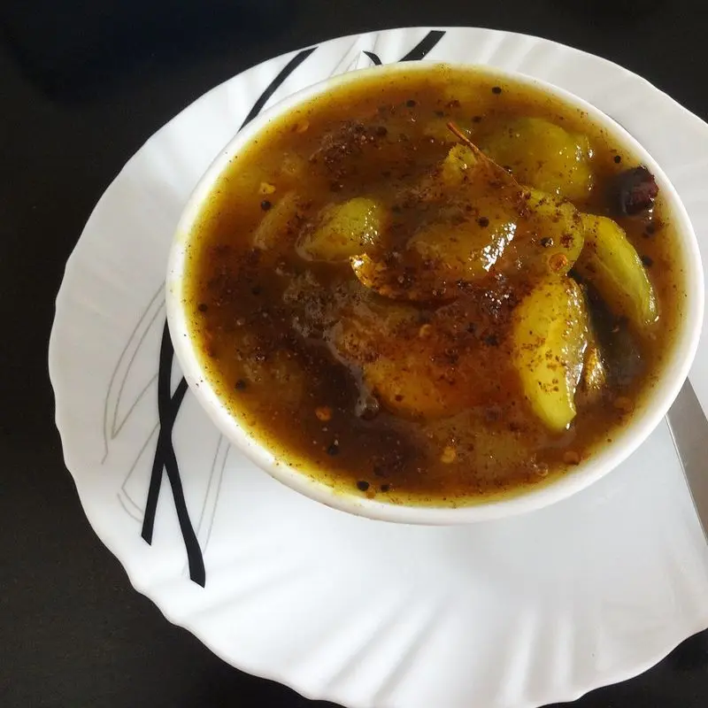 Cuenco blanco con chutney de mango dulce con trozos de fruta en salsa oscura