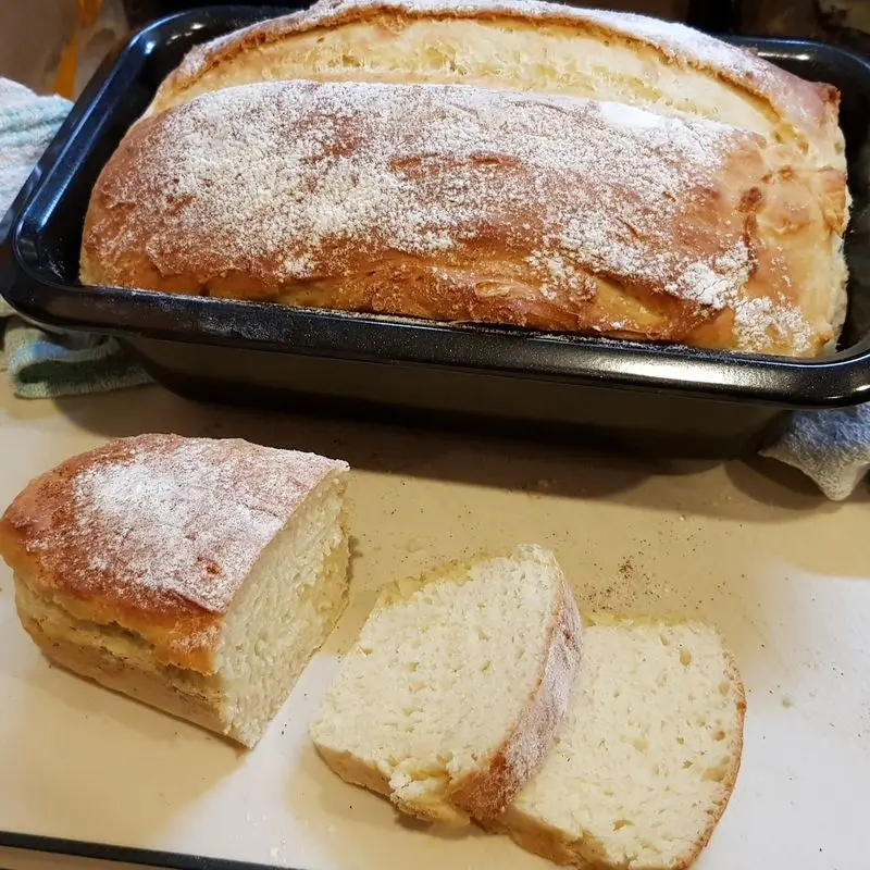 Pan de leche casero en molde con rebanadas cortadas sobre una tabla