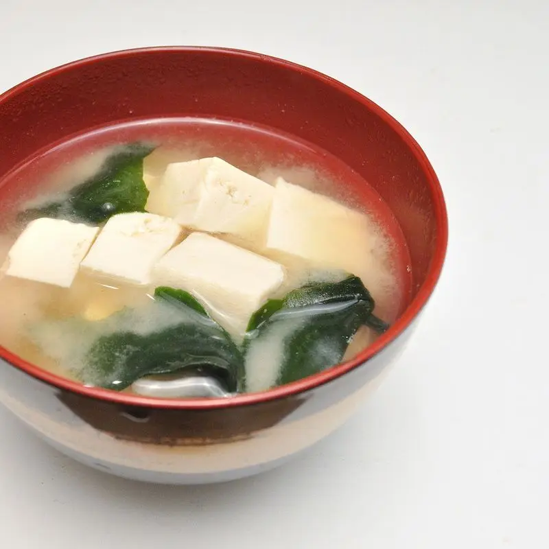 Cuenco rojo de sopa de miso con tofu en dados y alga wakame