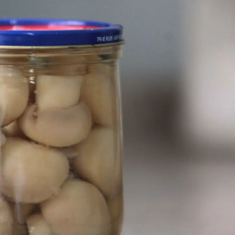 Frasco de cristal con champiñones enteros en conserva