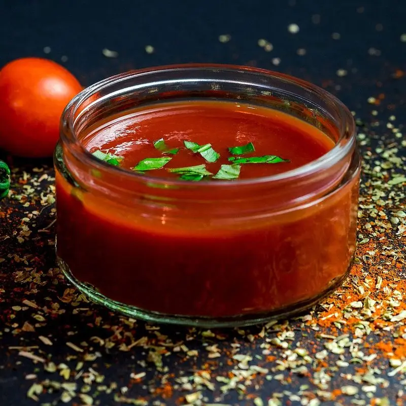 Tarro de cristal con salsa de tomate y tomates cherry con albahaca