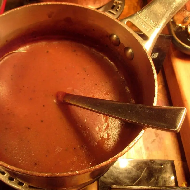 Cazo de cobre con salsa a la pimienta cremosa y una cuchara