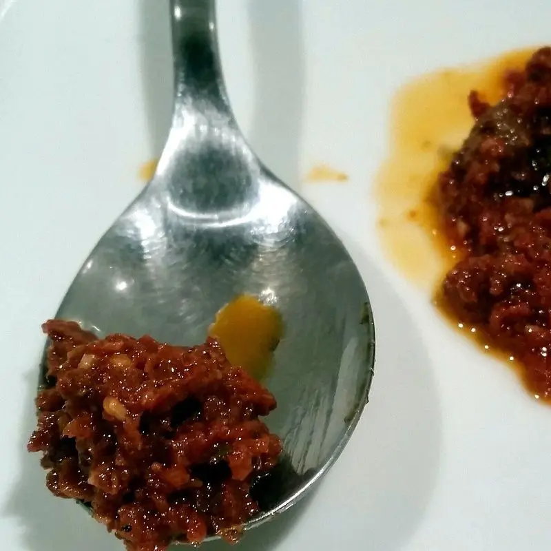 Pesto rojo de tomate seco en una cuchara y en un montoncito