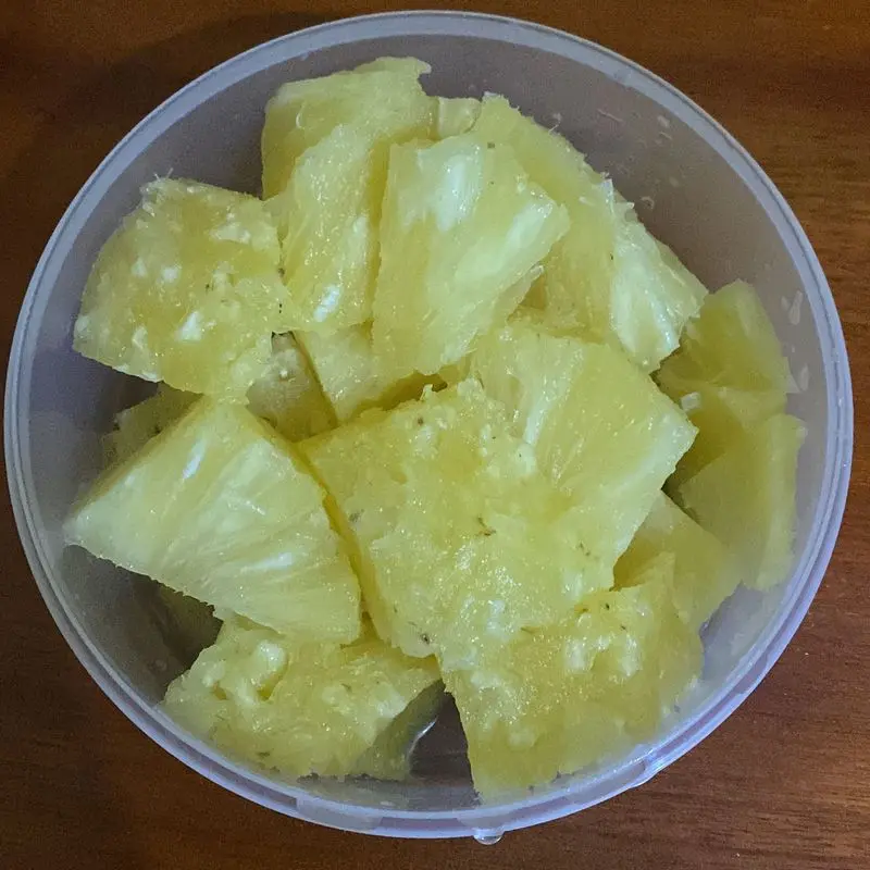 Trozos de piña amarilla en un recipiente transparente