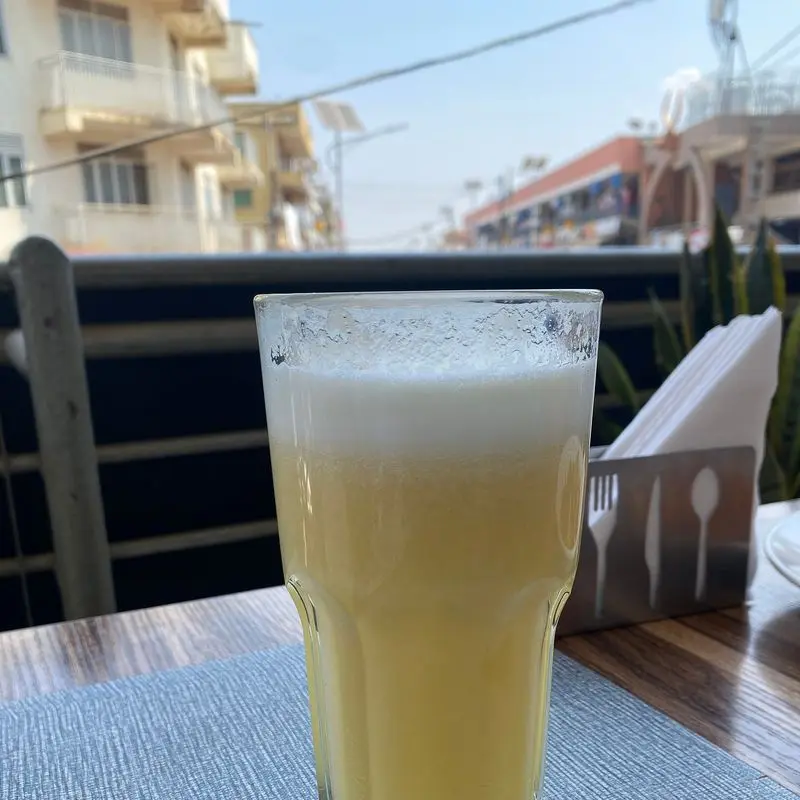 Vaso alto de zumo de piña con espuma sobre una mesa