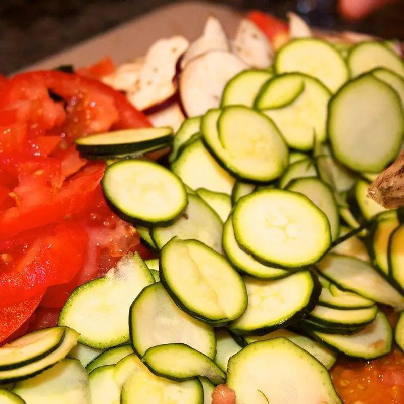 Rodajas de calabacín y tomate rojo troceado, verduras crudas para pisto
