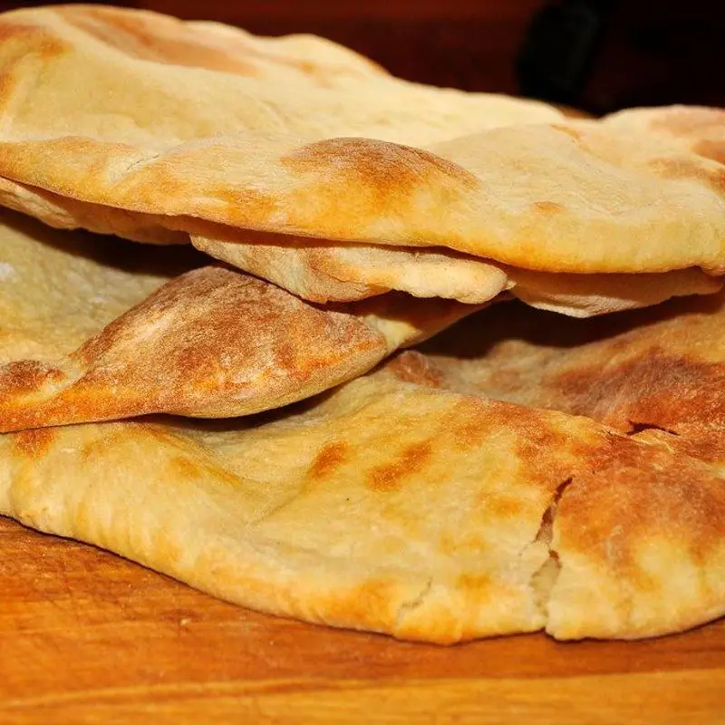 Panes de pita tostados apilados sobre una tabla de madera