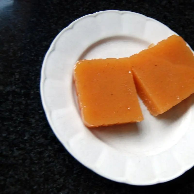 Dos porciones de carne de membrillo anaranjada en un plato blanco sobre fondo oscuro
