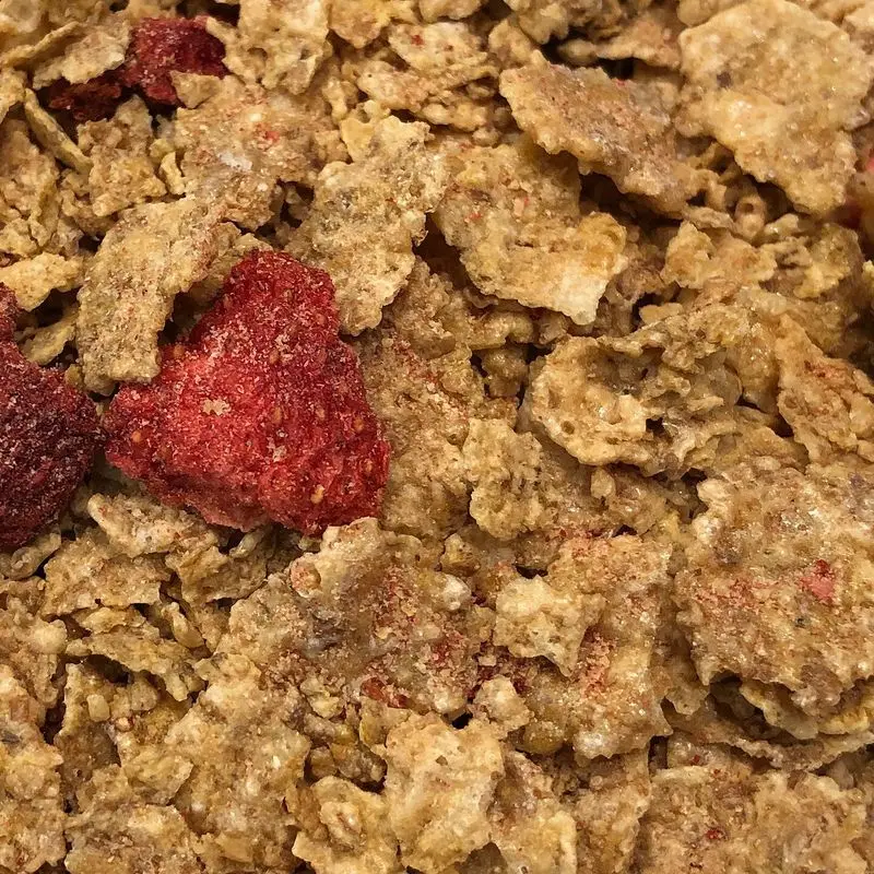 Copos de cereal integral con trozos de fresa liofilizada roja en primer plano