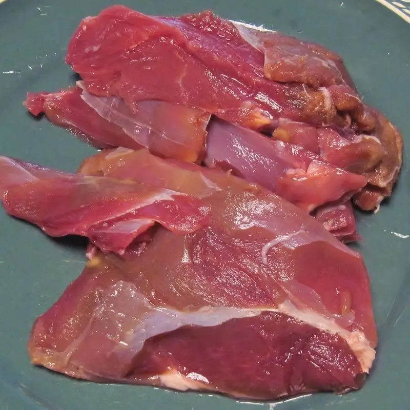Trozos de carne de ciervo cruda, de color rojo oscuro, deshuesada
