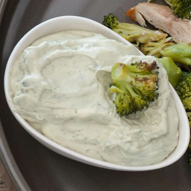 Fuente ovalada con salsa cremosa de queso azul junto a brócoli y pollo