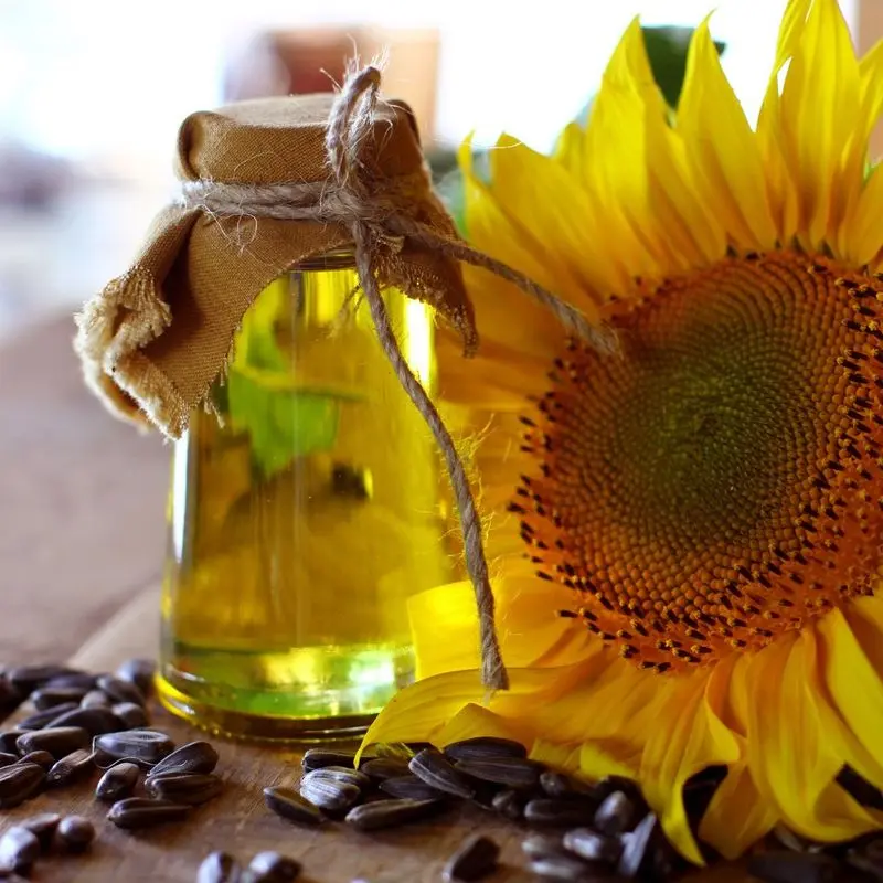 Botellita de aceite de semillas junto a un girasol y pipas