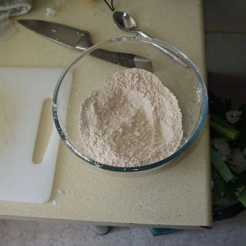 Cuenco de cristal con harina sobre una tabla de cocina blanca