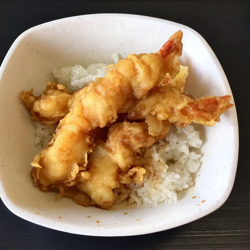 Gambas rebozadas en tempura sobre arroz en un cuenco blanco
