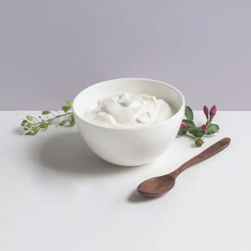 Cuenco blanco con skyr cremoso y una cuchara de madera