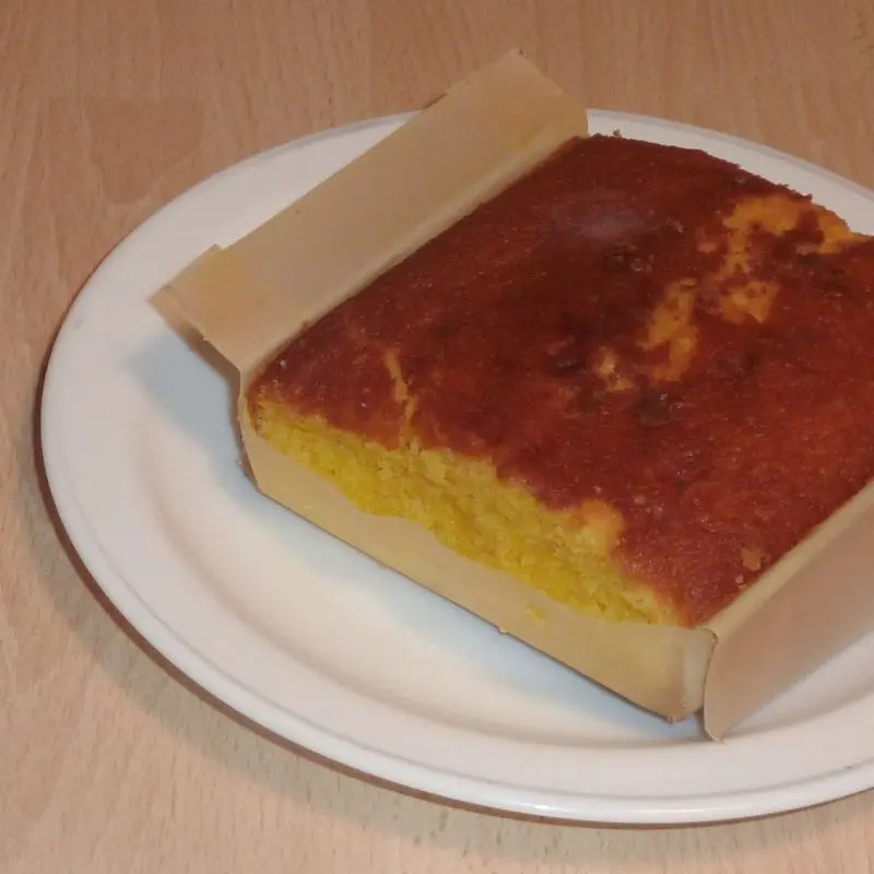 Sobao pasiego dorado en su papel de horno sobre un plato blanco