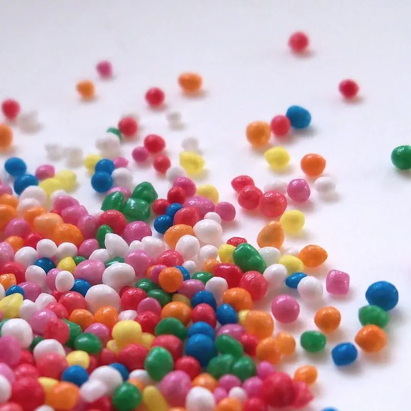 Fideos de colores para decorar repostería esparcidos sobre fondo blanco