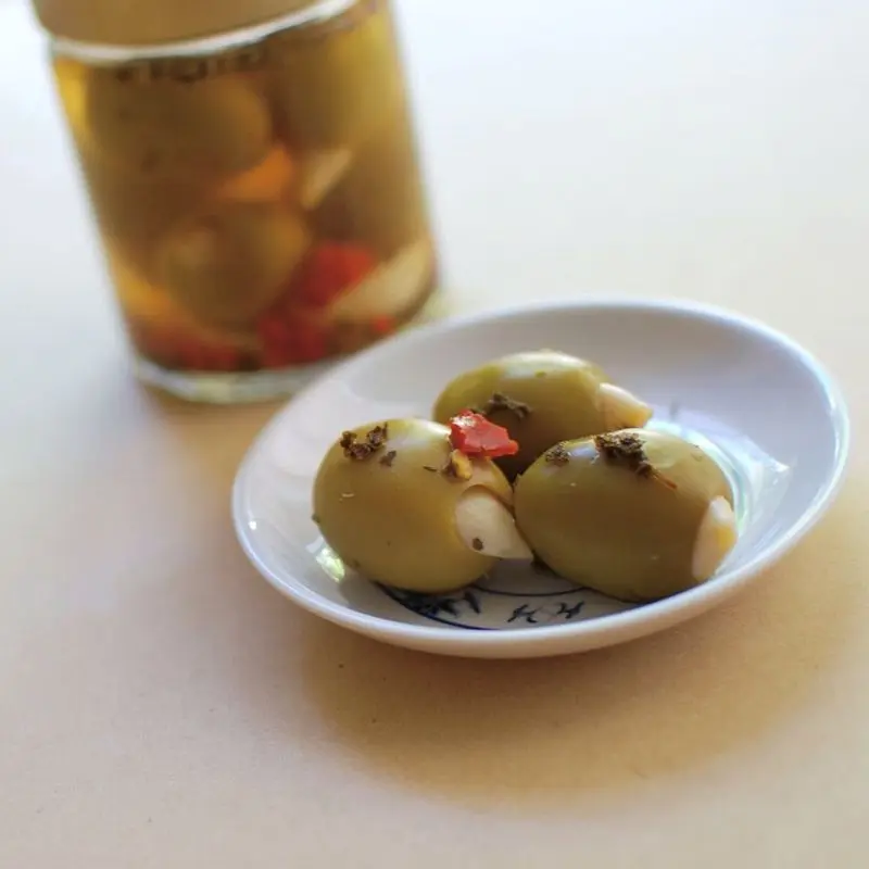 Aceitunas verdes rellenas de pimiento en un plato junto a un tarro