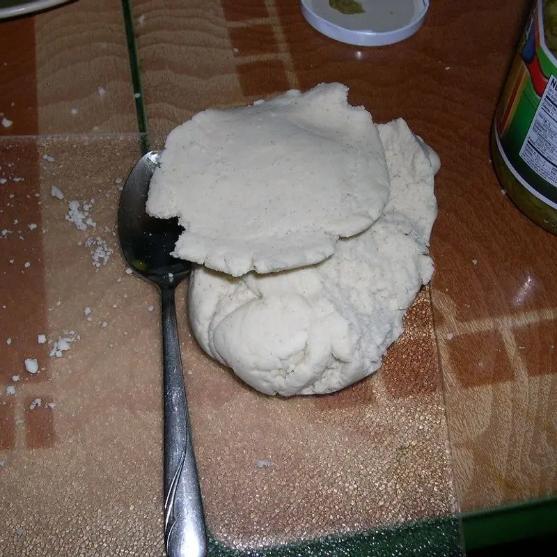 Masa fresca de pizza amasada sobre una encimera con harina y una cuchara